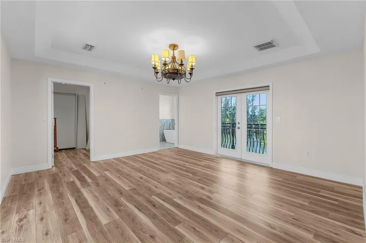 Upstairs master bedroom featuring a raised ceiling, light vinyl plank flooring, and french doors
