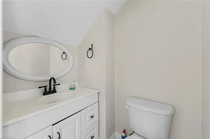 Guest bathroom with vanity, vaulted ceiling, and toilet