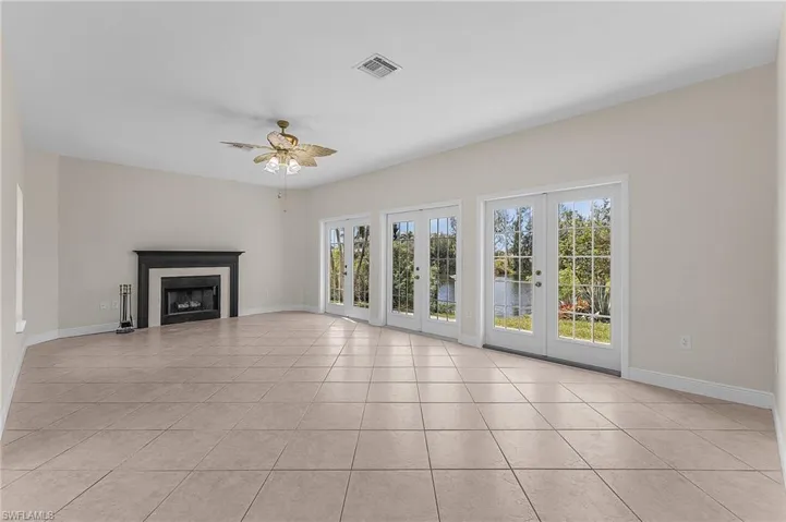 Family room with a wealth of natural light,   great water views, french doors, fireplace, ceiling fan, and light tile patterned flooring