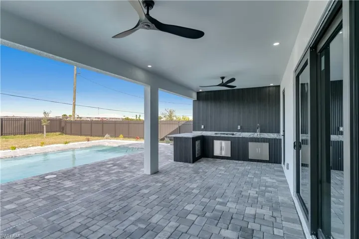 View of patio featuring an outdoor kitchen, ceiling fan, and a fenced in pool