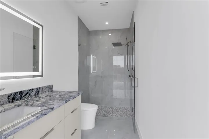 Bathroom with an enclosed shower, vanity, and toilet