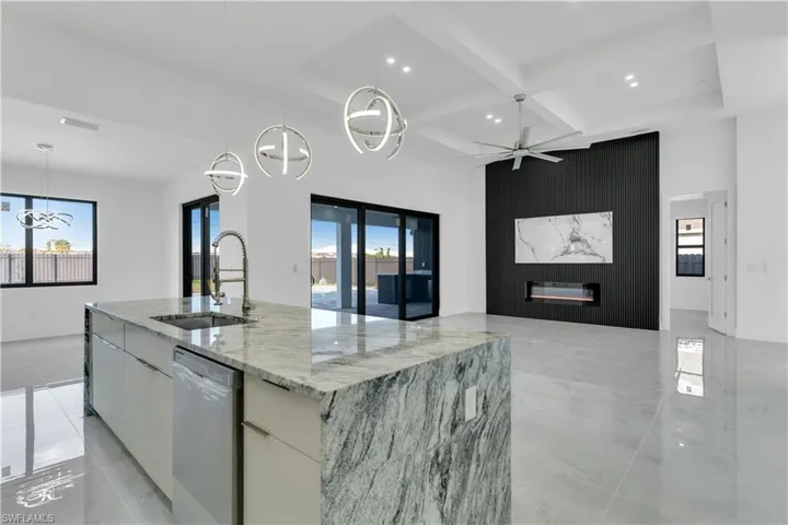 Kitchen featuring hanging light fixtures, white cabinetry, a large island with sink, and stainless steel dishwasher