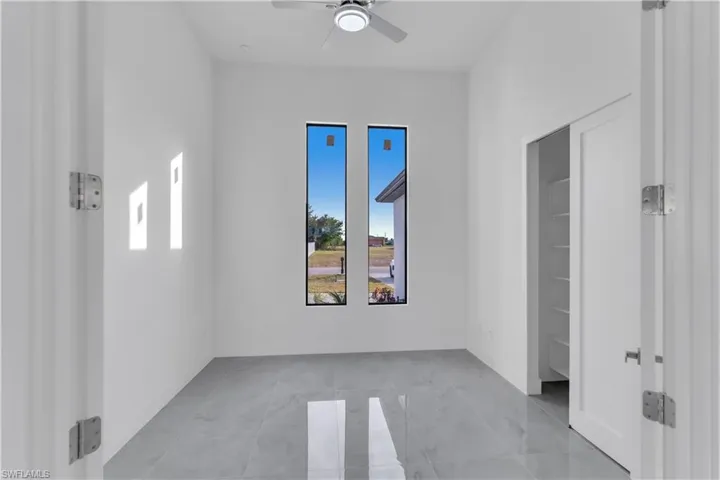 Tiled spare room featuring ceiling fan