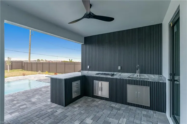 View of patio with ceiling fan, a fenced in pool, and sink
