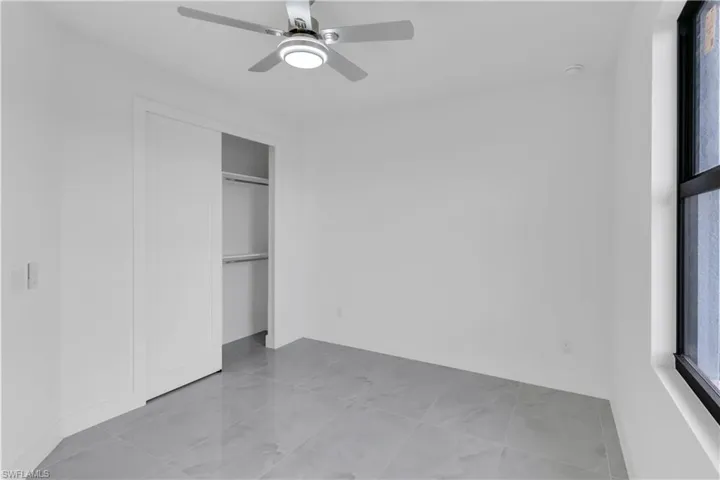 Unfurnished bedroom with ceiling fan and a closet