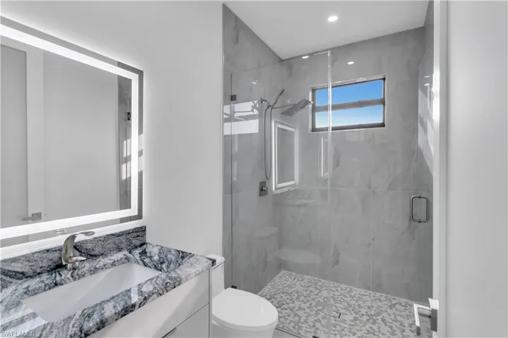 Bathroom with toilet, vanity, and a shower with shower door
