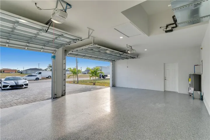 Garage featuring a garage door opener and electric water heater