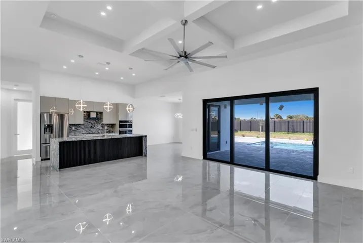 Kitchen with hanging light fixtures, a center island with sink, tasteful backsplash, stainless steel refrigerator with ice dispenser, and ceiling fan