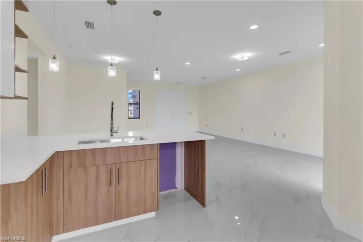 Kitchen with decorative light fixtures, kitchen peninsula, and sink