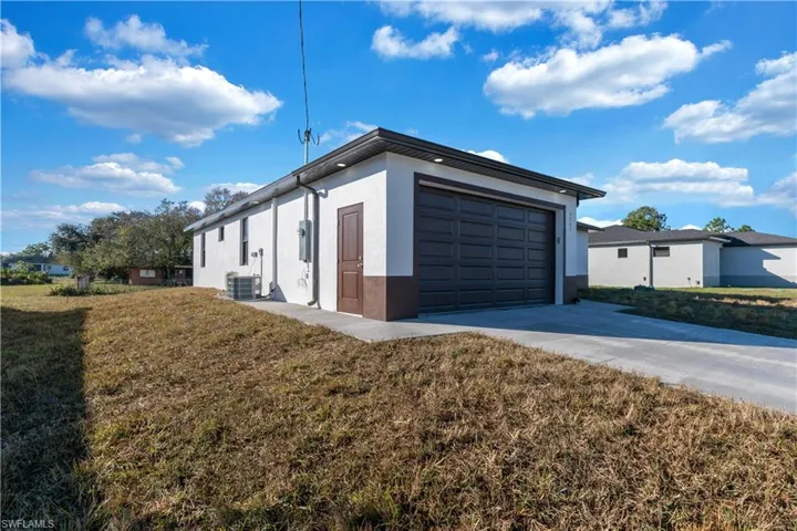 View of home's exterior featuring a lawn, a garage, and central AC