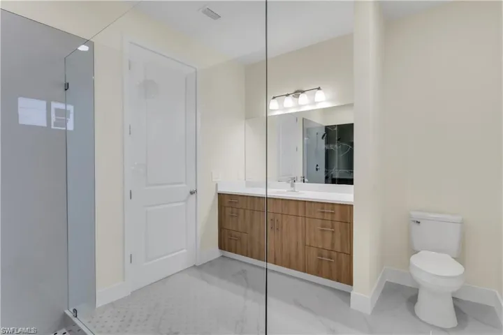 Bathroom featuring toilet, an enclosed shower, and vanity