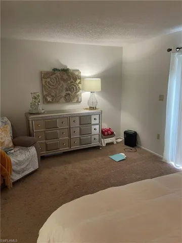 Bedroom with dark carpet and a textured ceiling