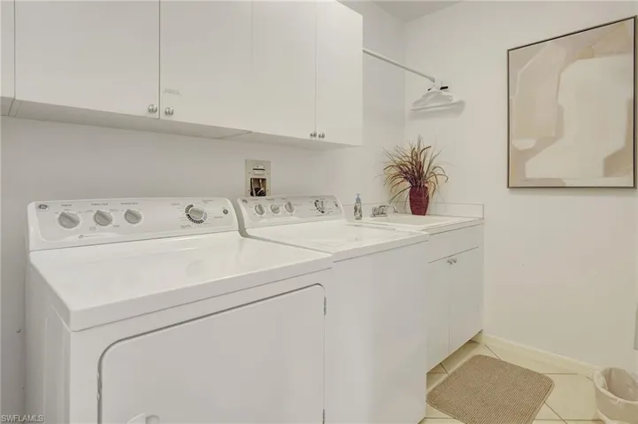 Laundry room with light tile patterned flooring, sink, cabinets, and separate washer and dryer