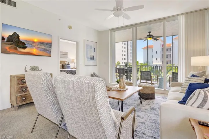 Living room with ceiling fan, a wall of windows, and carpet floors