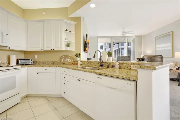 Kitchen featuring kitchen peninsula, white cabinets, white appliances, sink, and light colored carpet