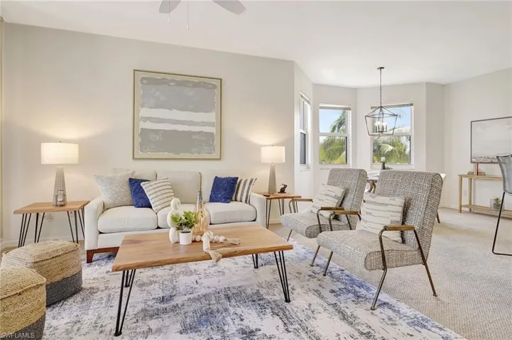 Carpeted living room featuring ceiling fan with notable chandelier