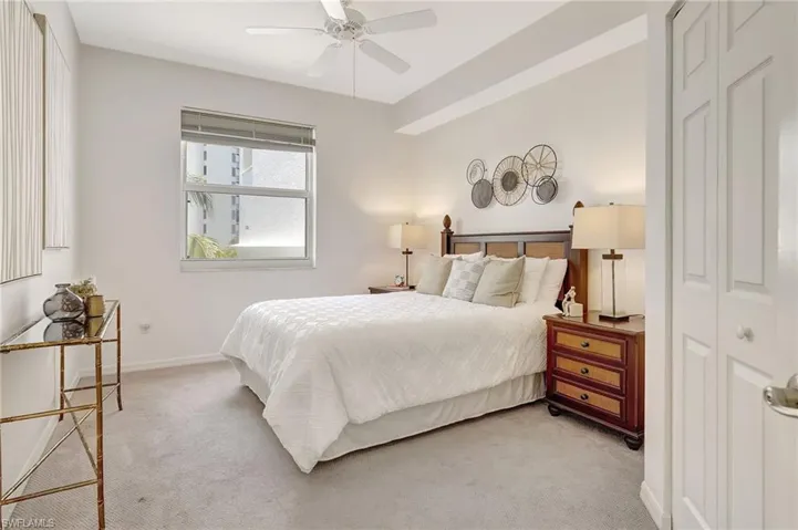 Carpeted bedroom with ceiling fan and a closet