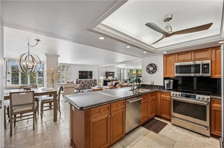 Kitchen featuring a raised ceiling, stone tile floors, a sink, and appliances with stainless steel finishes
