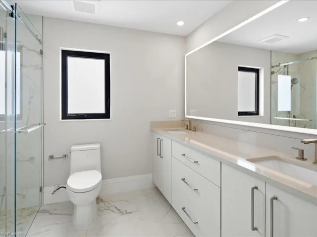 Full bathroom featuring a marble finish shower, marble finish floor, toilet, and a sink