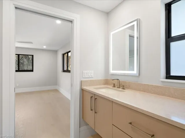 Bathroom with vanity, recessed lighting, wood finished floors, and baseboards