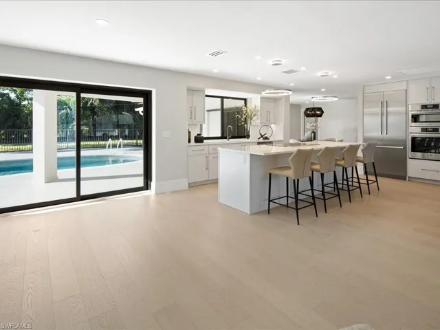 Kitchen featuring white cabinets, light wood-type flooring, appliances with stainless steel finishes, and a center island