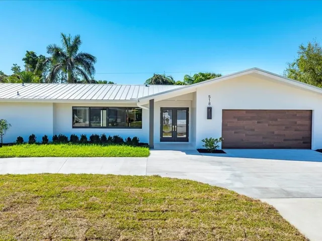 View of front of home featuring stucco siding, french doors, concrete driveway, and a garage