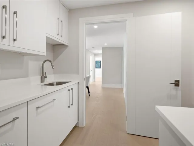 Kitchen featuring light wood-style flooring, a sink, white cabinetry, recessed lighting, and light countertops