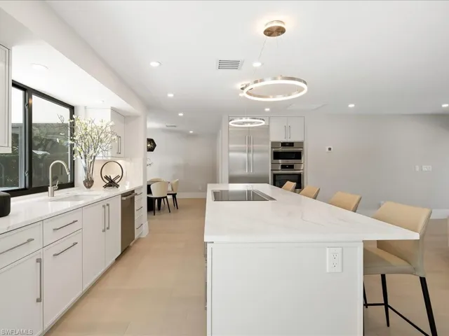 Kitchen featuring visible vents, a kitchen island with sink, a sink, appliances with stainless steel finishes, and a kitchen breakfast bar