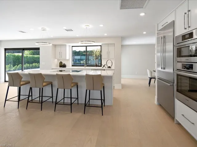 Kitchen with tasteful backsplash, visible vents, a kitchen island, stainless steel appliances, and white cabinetry