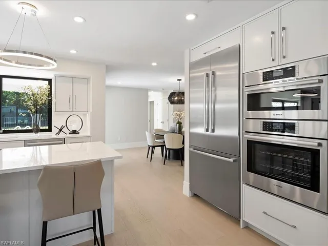 Kitchen with light wood-style flooring, light stone counters, recessed lighting, appliances with stainless steel finishes, and decorative backsplash