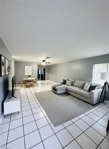 Living room with light tile patterned flooring and ceiling fan