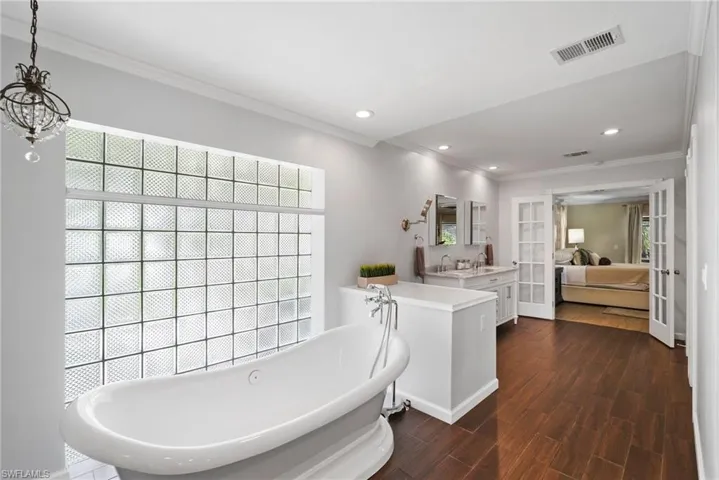 Bathroom featuring wood-type flooring, a bathing tub, ornamental molding, and vanity