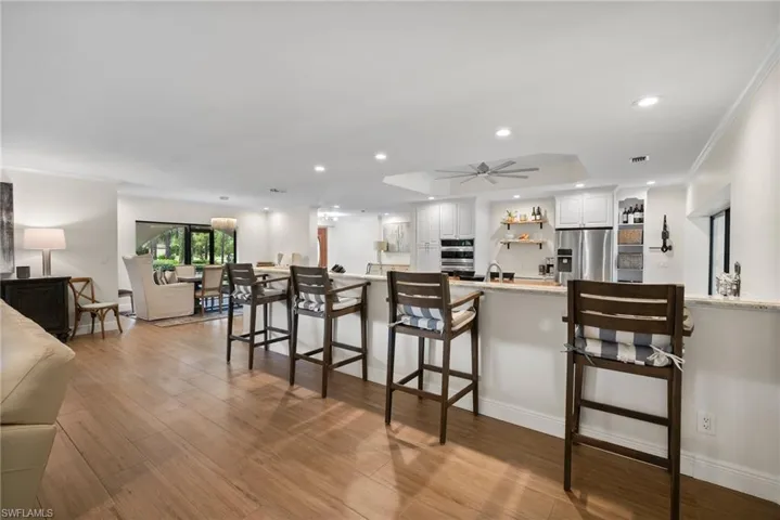 Kitchen with light wood-type flooring, appliances with stainless steel finishes, white cabinets, and a breakfast bar