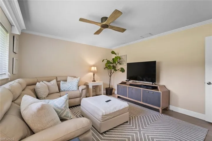 Living room featuring ceiling fan, dark hardwood / wood-style floors, and crown molding