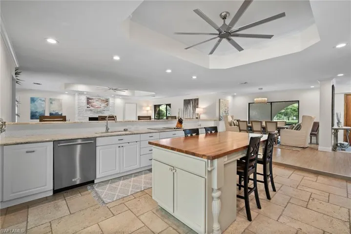 Kitchen featuring ceiling fan, dishwasher, a kitchen island, and wooden counters