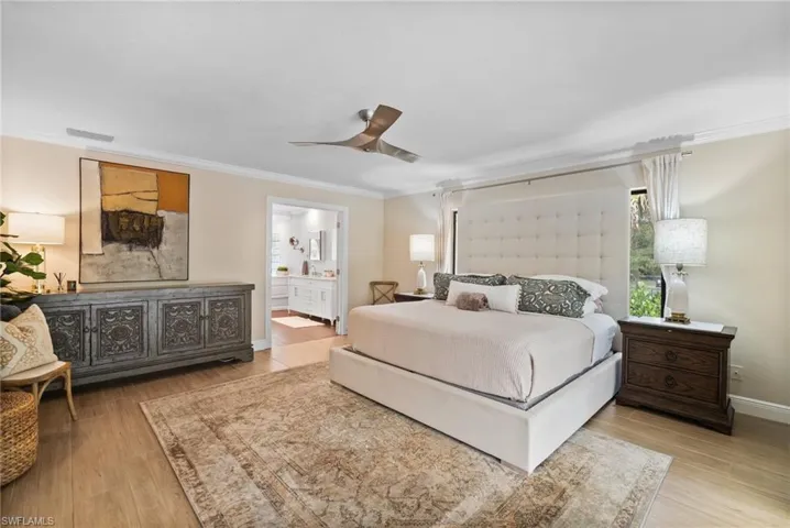 Bedroom featuring crown molding, light hardwood / wood-style flooring, ceiling fan, and ensuite bathroom