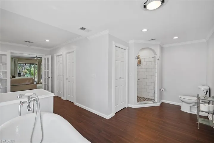 Bathroom featuring separate shower and tub, toilet, ornamental molding, and hardwood / wood-style floors