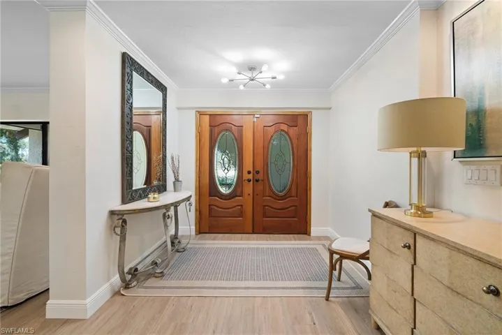 Foyer entrance with crown molding and light hardwood / wood-style floors