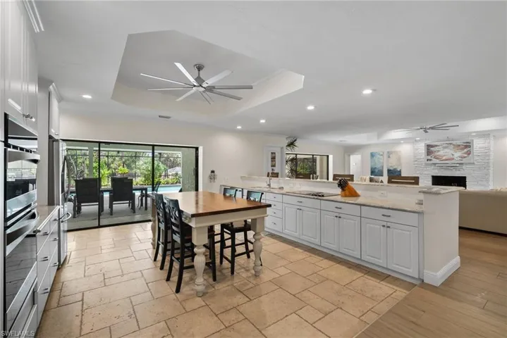 Dining room with a raised ceiling, ceiling fan, and a large fireplace