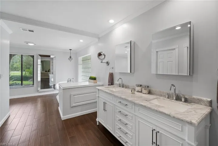Bathroom featuring crown molding, vanity, and wood-type flooring