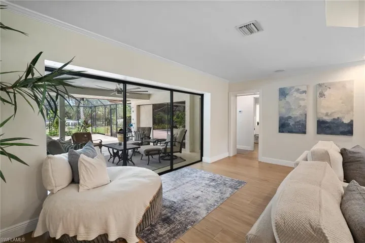 Living room with light wood-type flooring and crown molding