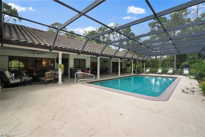 View of swimming pool featuring glass enclosure, ceiling fan, an outdoor living space, and a patio