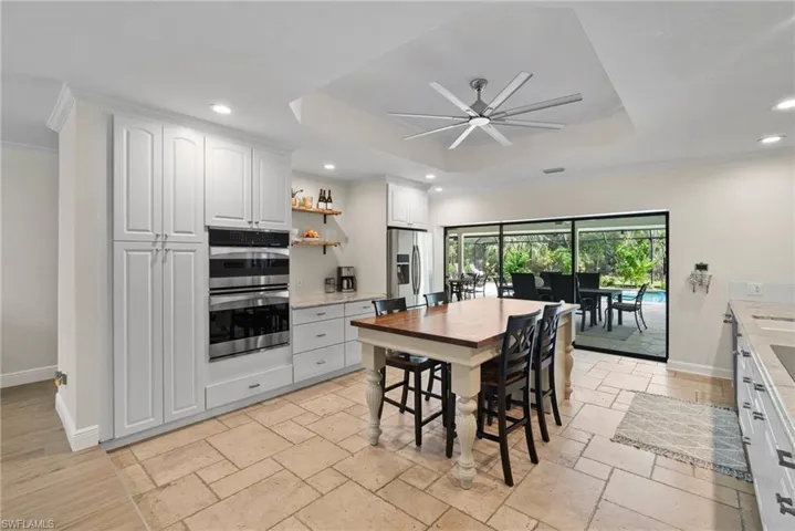 Dining room featuring ceiling fan, ornamental molding, a tray ceiling, and light tile patterned flooring