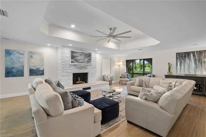 Living room with a raised ceiling, light wood-type flooring, and a fireplace