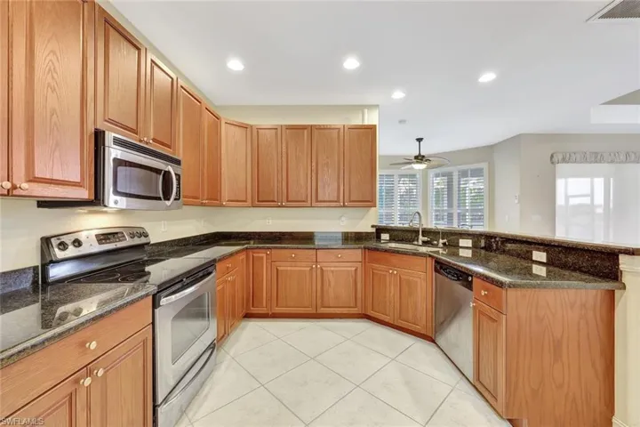 Kitchen with light tile patterned flooring, visible vents, a peninsula, appliances with stainless steel finishes, and a sink