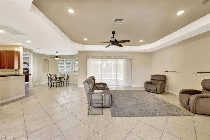 Living area featuring a tray ceiling, visible vents, ceiling fan, and light tile patterned floors