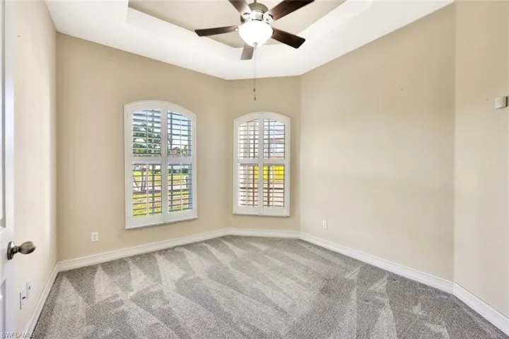 Carpeted empty room with baseboards, a ceiling fan, and a raised ceiling