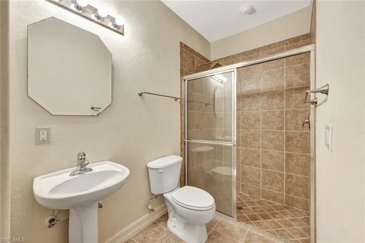 Bathroom featuring toilet, a stall shower, and tile patterned flooring