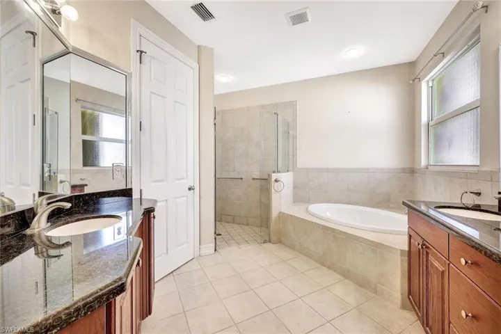 Bathroom featuring a stall shower, visible vents, tile patterned flooring, and a sink