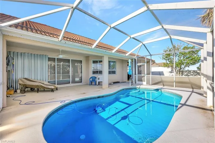 View of pool featuring glass enclosure, ceiling fan, a patio, and a fenced in pool